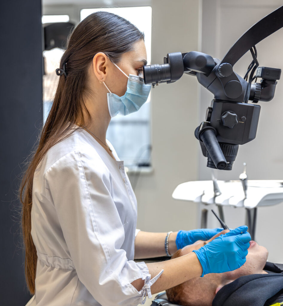 young female dentist treating patient's teeth with dental microscope. dentistry concept.